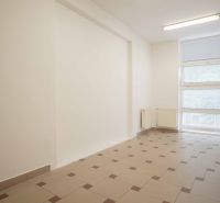 The interior of an office with large windows and light-colored tiles on the floor.
