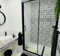 Bathroom with a shower and patterned tiles in a studio apartment.