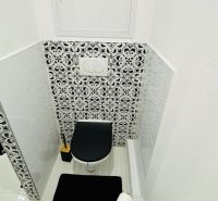 A toilet with a black-and-white tile pattern in a studio apartment.