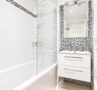 Bathroom with a bathtub and mosaic tiles in a 2-room apartment, elegant design.