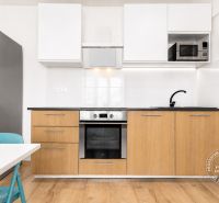 A kitchen in a 2-room apartment with a wood-patterned floor and a stainless steel refrigerator.