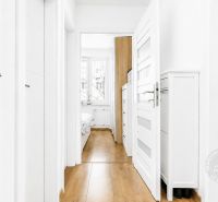 A bright hallway with a wood-patterned floor and entrances to rooms in a 2-room apartment.