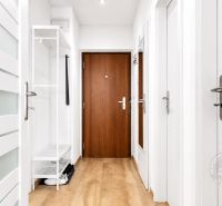 A white hallway in a 2-room apartment with wood-patterned flooring and security doors.