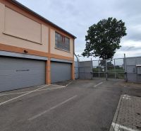 The exterior of the warehouse and halls on Coburgova Street in Trnava, with large gates and a tree.