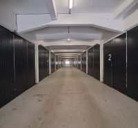 Narrow corridor with numbered sections in warehouses and halls, illuminated by fluorescent lights.