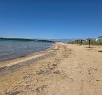 Sandy beach with reed umbrellas in Privlaka, with blue sky and sea.