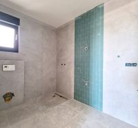 A bathroom in a 3-room apartment with gray tiles and a blue mosaic on the wall.