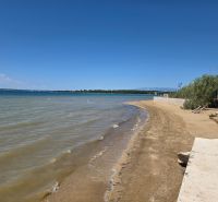 A sandy beach by the sea in Privlaka with a clear blue sky and water.