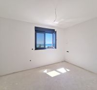 An empty room without furniture with a window and a sea view in a 3-room apartment.