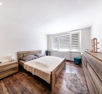 A bedroom in a 3-room apartment with a bed, a dresser, and a floor with a wooden decor.