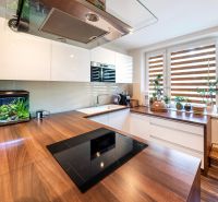 A kitchen in a 3-room apartment with a wooden decor floor and windows with plants.