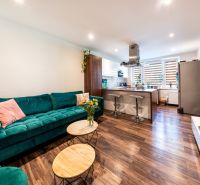 Living room with a kitchenette in a 3-room apartment, wooden decor flooring, green sofa.