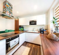 A kitchen in a 3-room apartment with a wood-decor floor, houseplants, and modern appliances.