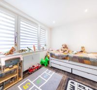 Children's room in a three-room apartment with a wooden decor floor, full of toys and teddy bears.
