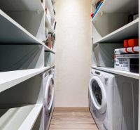 Storage space with shelves and a washing machine in a 3-room apartment with wood-patterned flooring.