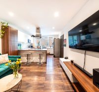 Living room in a 3-room apartment with a TV, sofa, and kitchen, floor with wood decor.