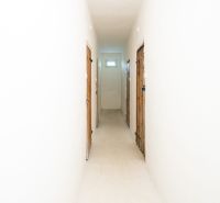 Hallway in a 3-room apartment with white walls and doors to the rooms.