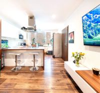 3-room apartment with a kitchen and wooden decor flooring, bar stools, sofa.