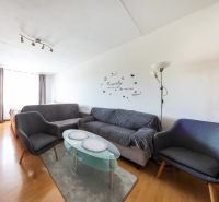 Living room with wood-patterned flooring in a 3-room apartment, gray sofas, glass table.