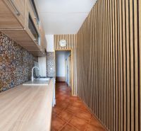 A kitchen with a wooden decor floor, stone tiles, and cabinets in a 3-room apartment.