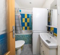 A bathroom in a 3-room apartment with colorful tiles and a washing machine.