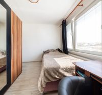 A room with a bed, a desk, and a wardrobe with a mirror in a three-room apartment.