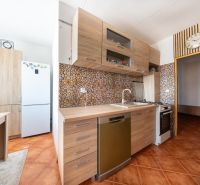 A kitchen in a 3-room apartment with a wood-patterned floor and ceramic tiles.