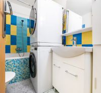 A bathroom in a 3-room apartment with a washing machine, dryer, and colorful tiles.