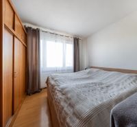 A bedroom with a bed, a large wardrobe, and a floor with a wooden decor in a 3-room apartment.