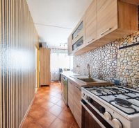 A kitchen in a 3-room apartment with a kitchen unit and tiles with a stone decor.