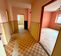 A bright interior of a family house with a tiled floor, pink walls, and wooden paneling.