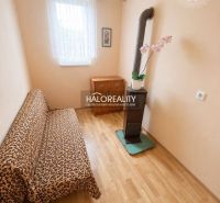 A room in a family house with a wooden decor floor, a sofa, and a stove.