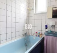 Bathroom with a bathtub and a sink in a family house. White tiles and a light blue bathtub.