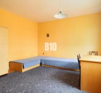 A room in a family house with blue beds, a desk, and a carpet.