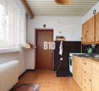 A kitchen in a family house with wooden decor and white curtains.