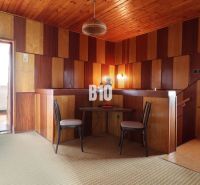 Interior of a family house with a wooden ceiling, panel walls, and two chairs.