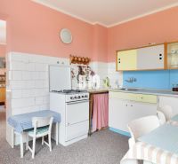 A kitchen in a family house with retro furniture, colorful cabinets, dining table.