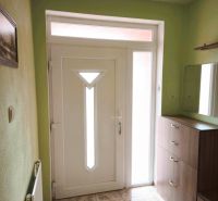 Entrance door in a family house with a white frame and decorative tiles.