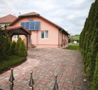 A family house in Martin nad Žitavou on Hlavná Street with solar panels and a paved courtyard.