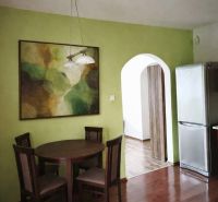 Dining area in a family house with a wooden decor floor and a colorful painting.