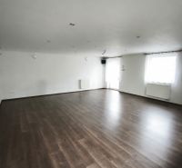 A spacious room in a family house with a wooden decor floor and white walls.