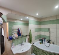 The bathroom of a 3-room apartment with a bathtub, sink, and tiles in shades of green.
