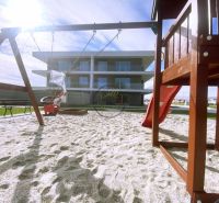 A children's playground with sand near a 2-room apartment in Galanta, with a slide and a swing.