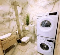 A bathroom with a washing machine and dryer in a 2-room apartment with marble tiles.
