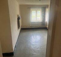 A room in a family house with a concrete floor and a window with incoming light.