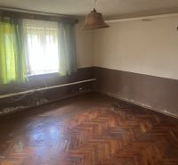 A room in a family house with a wooden floor design and green curtains.
