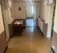 A hallway in a family house with a wooden decor floor, a table, and decorations.