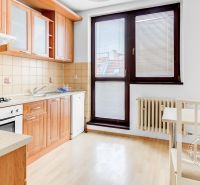A kitchen with a wooden decor in a 2-room apartment includes a dining area and appliances.