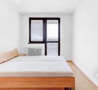 Bedroom in a two-room apartment with a bed, nightstand, and window.
