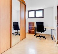 A workspace in a 2-room apartment with a wooden decor floor and a wardrobe with sliding doors.